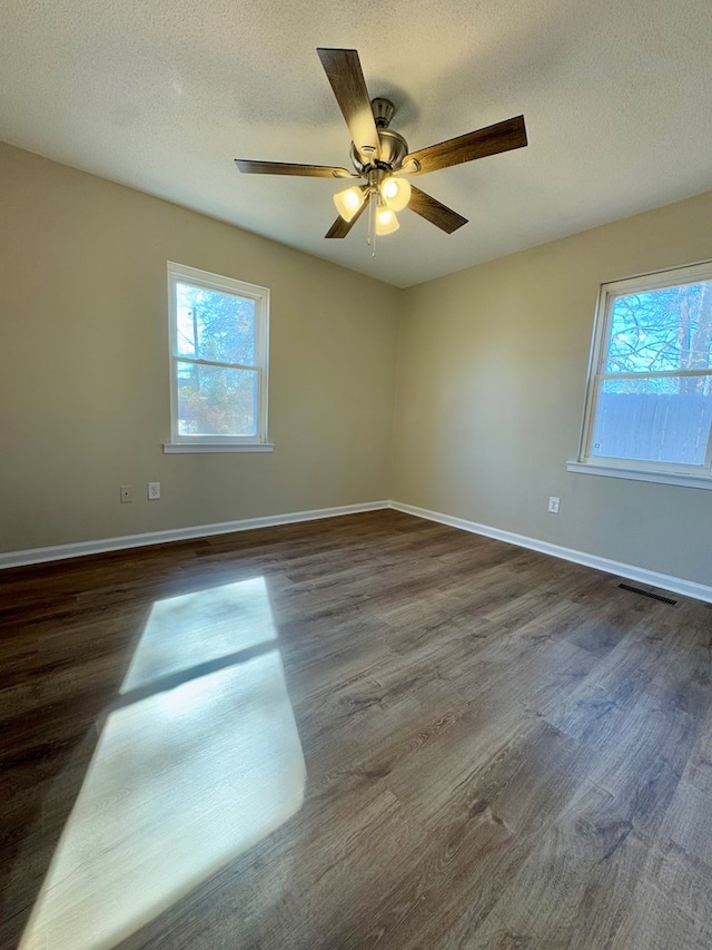 unfurnished room featuring plenty of natural light, dark hardwood / wood-style floors, and a textured ceiling