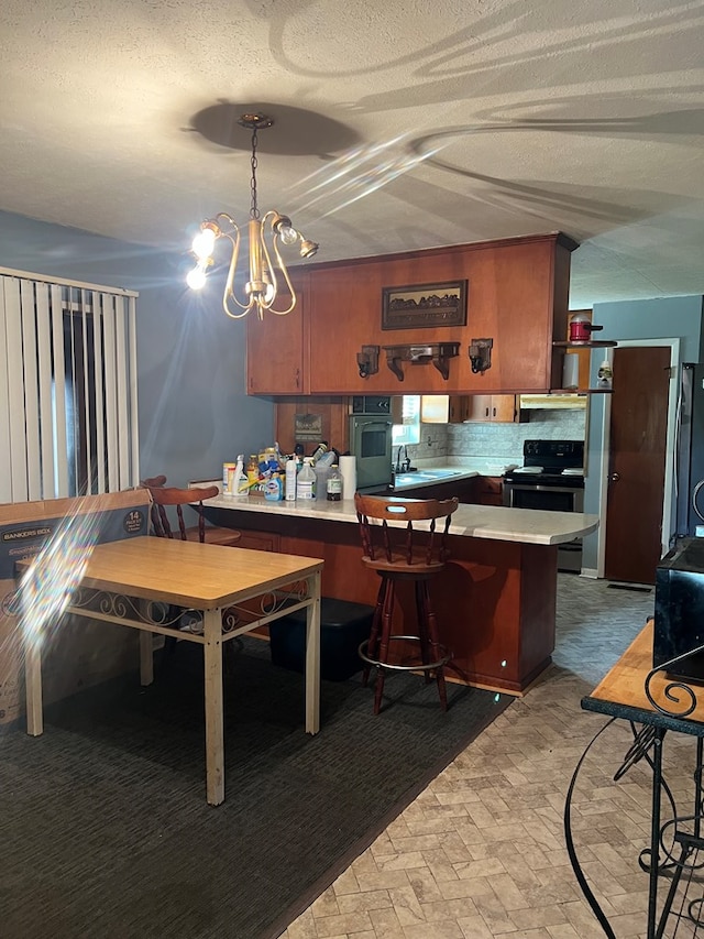 kitchen with pendant lighting, stainless steel fridge, oven, backsplash, and electric stove