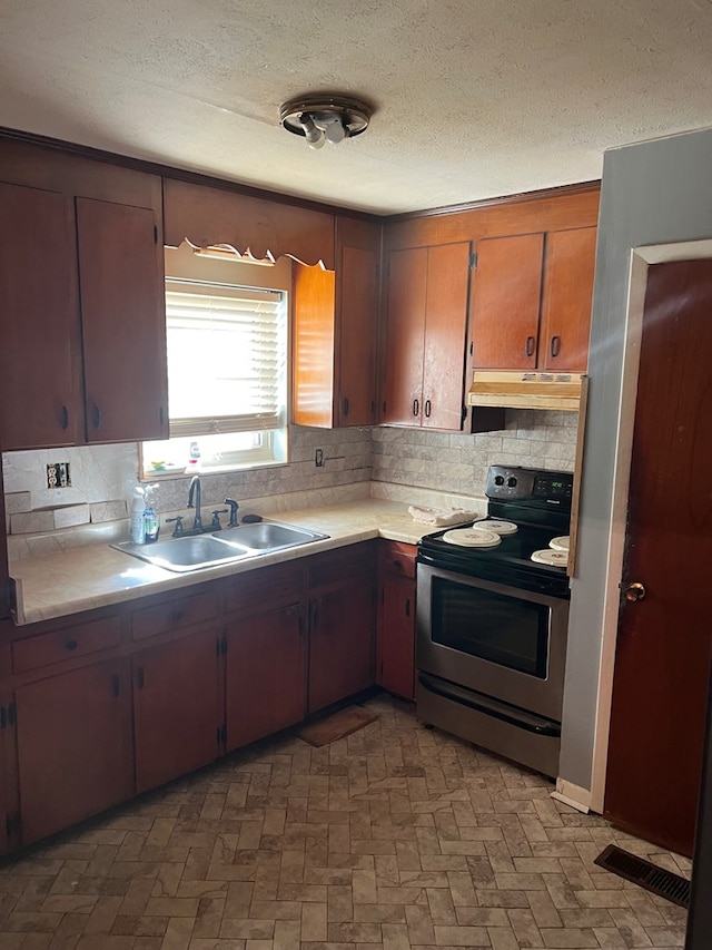 kitchen featuring sink, decorative backsplash, a textured ceiling, and stainless steel electric range oven