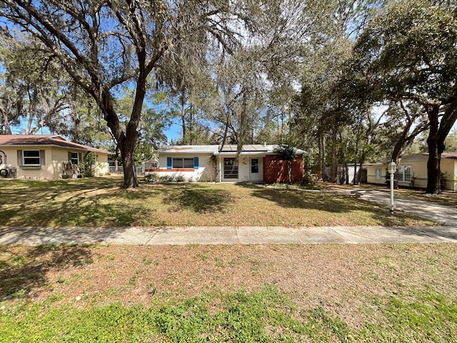 single story home with solar panels, a front yard, and stucco siding