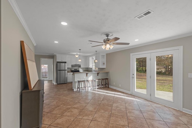 kitchen featuring a breakfast bar, decorative light fixtures, white cabinetry, stainless steel fridge, and kitchen peninsula