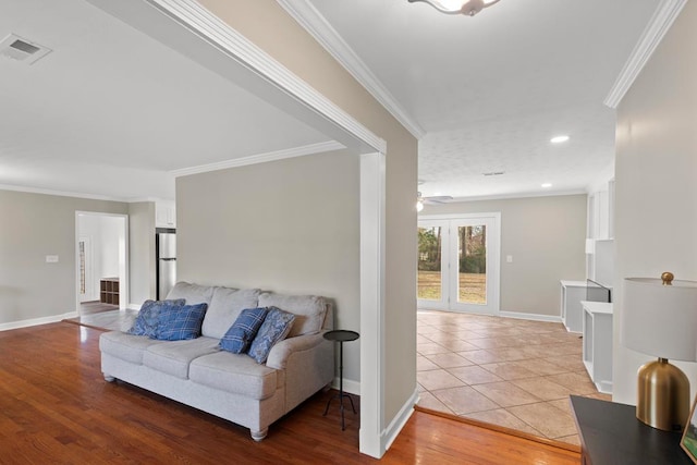 living room featuring ceiling fan, ornamental molding, and light wood-type flooring