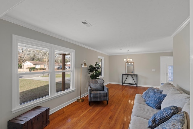 living room with wood-type flooring, ornamental molding, and a chandelier