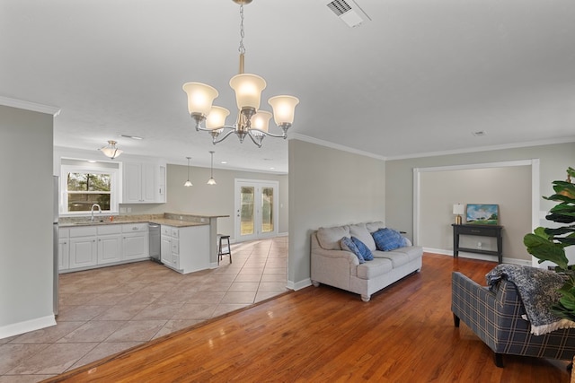 living room featuring sink, crown molding, a notable chandelier, and light wood-type flooring