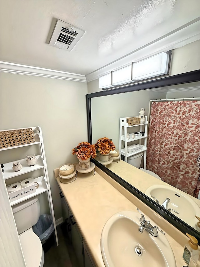 bathroom with toilet, vanity, and ornamental molding