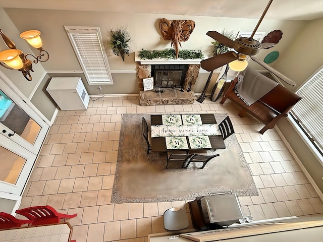 tiled living room with ceiling fan and a fireplace