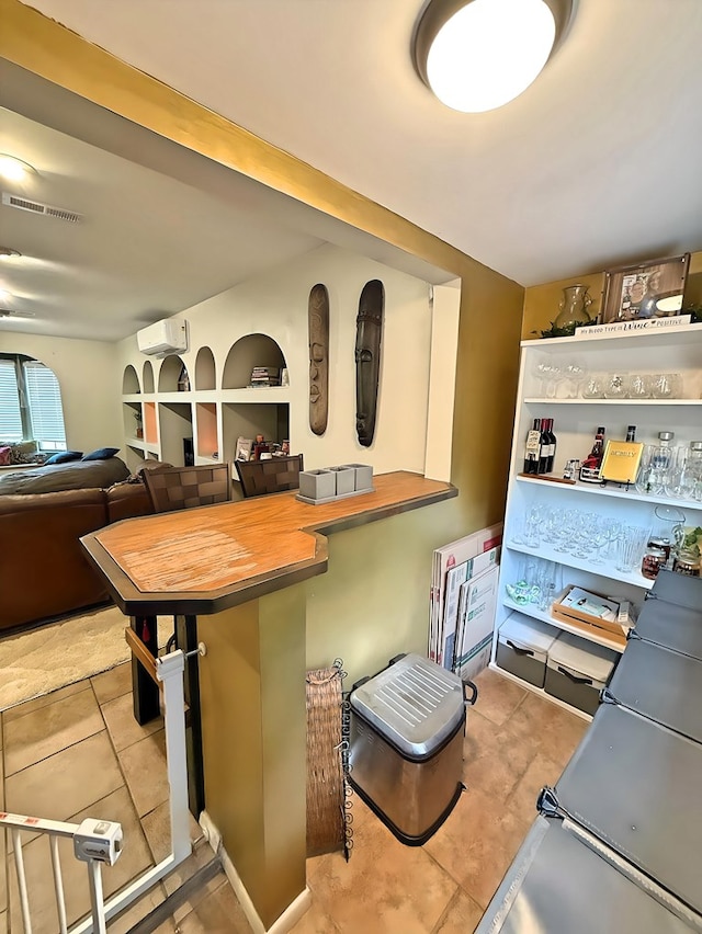 kitchen featuring tile patterned floors, butcher block counters, a kitchen breakfast bar, kitchen peninsula, and a wall mounted air conditioner