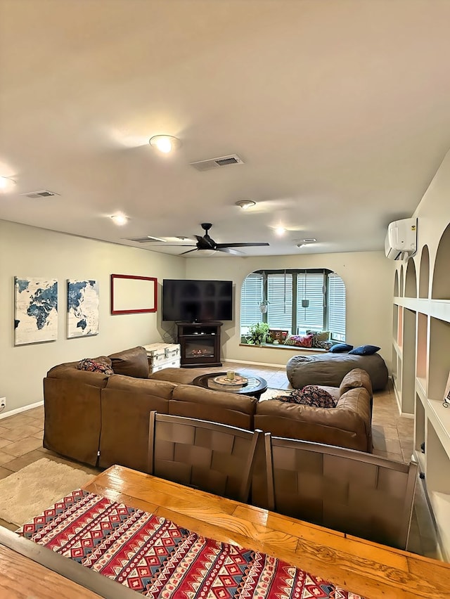 tiled living room with ceiling fan, a wall unit AC, and a fireplace