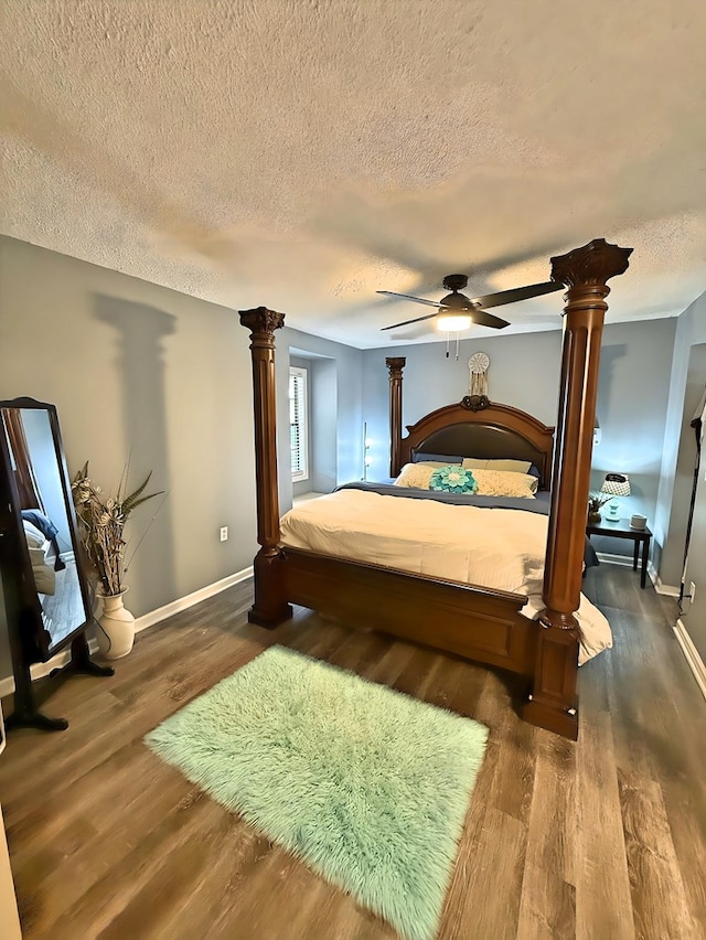 bedroom featuring ceiling fan, a textured ceiling, dark hardwood / wood-style floors, and decorative columns