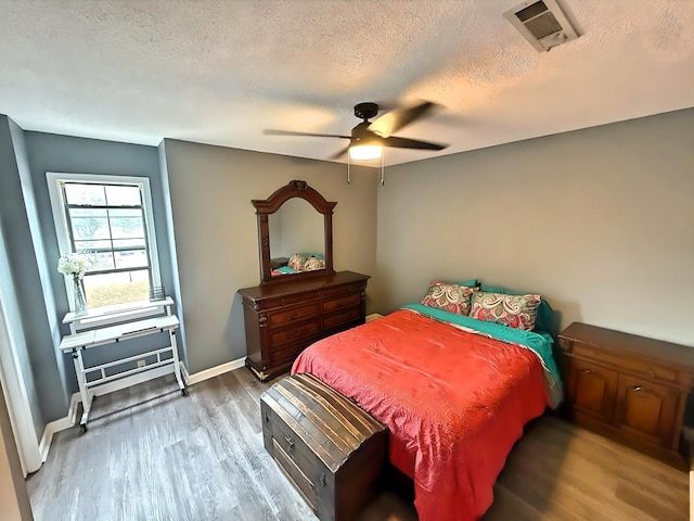 bedroom with ceiling fan, a textured ceiling, and hardwood / wood-style flooring