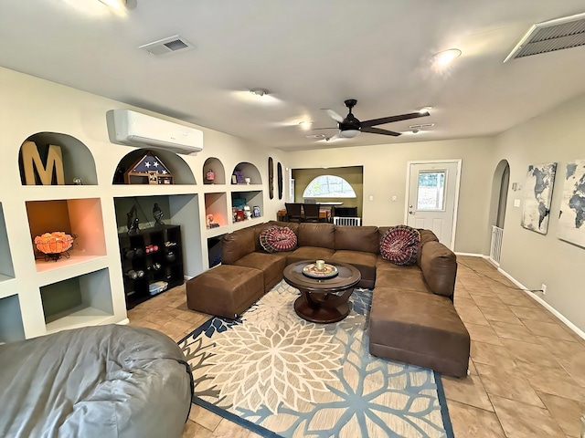 living room featuring ceiling fan, built in shelves, an AC wall unit, and light tile patterned flooring