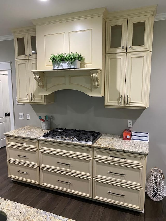 kitchen featuring stainless steel gas stovetop, dark hardwood / wood-style flooring, ornamental molding, and light stone counters