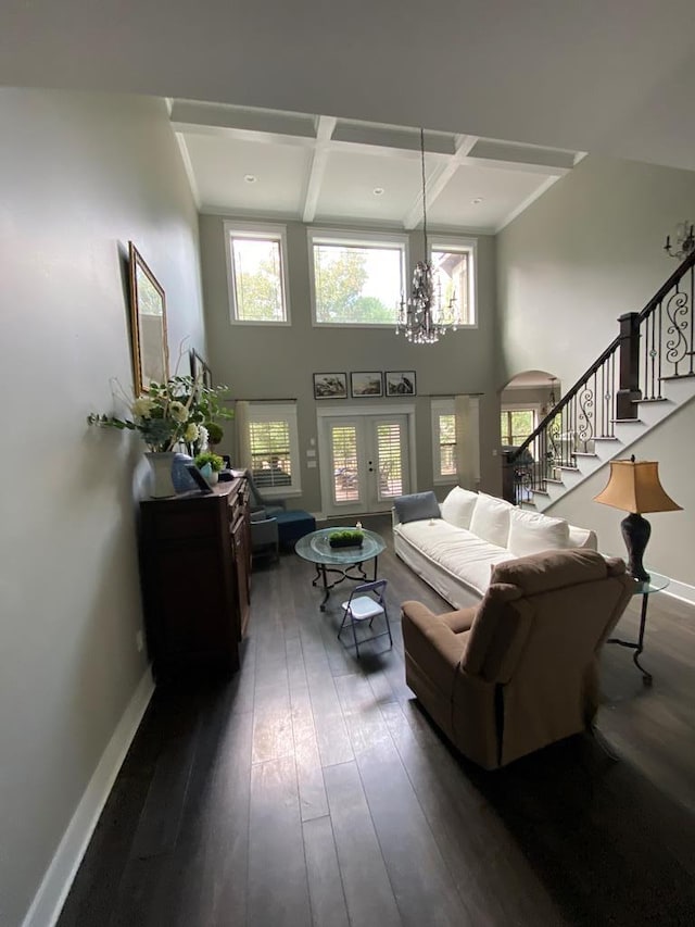 living room featuring french doors, dark wood-type flooring, coffered ceiling, beamed ceiling, and a notable chandelier