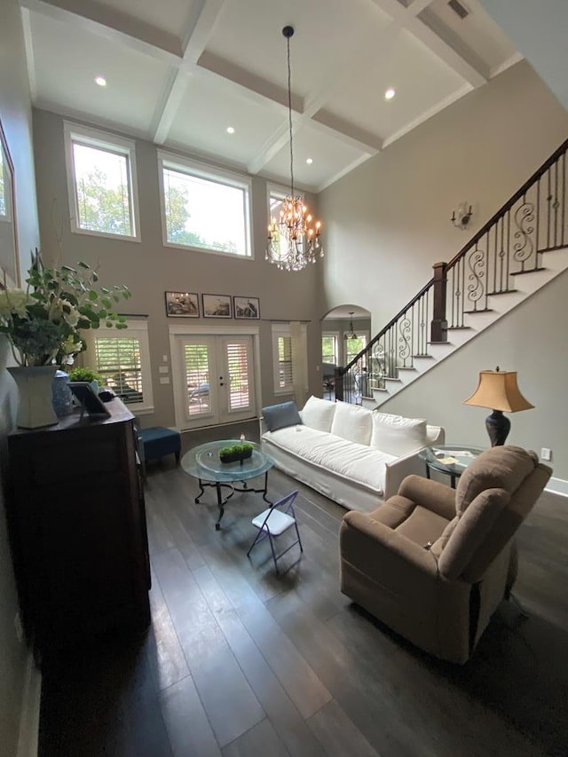 living room with a high ceiling, coffered ceiling, an inviting chandelier, dark hardwood / wood-style flooring, and beamed ceiling