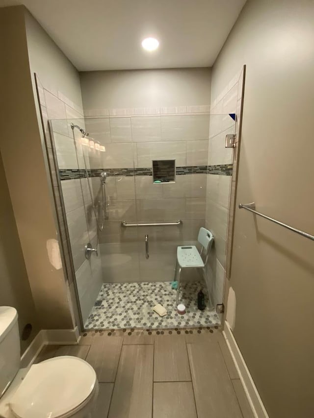 bathroom with hardwood / wood-style floors, toilet, and a shower with shower door