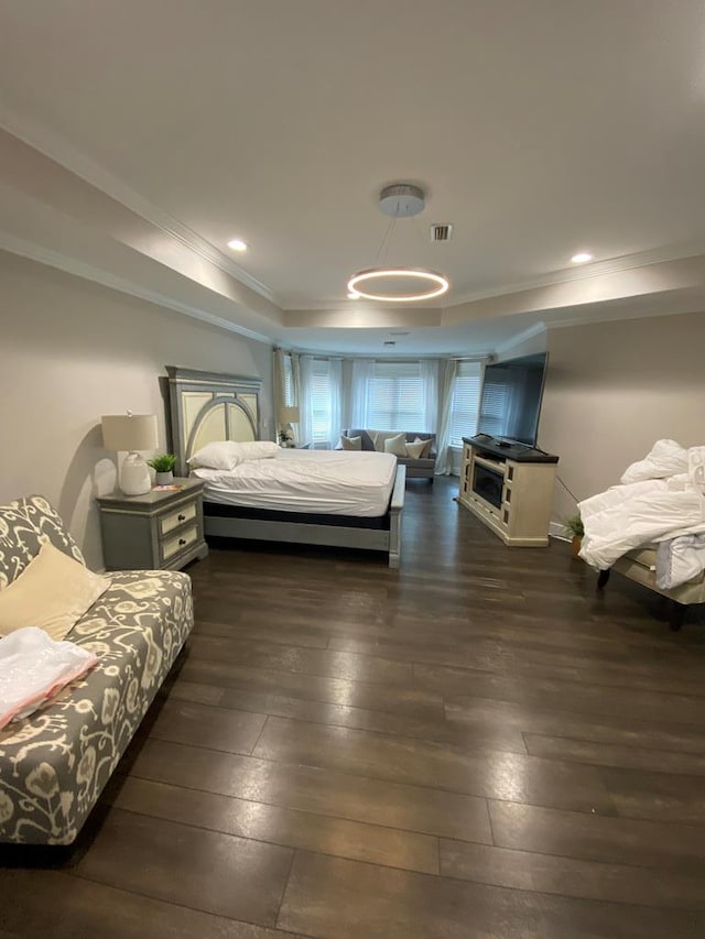 bedroom featuring a tray ceiling, dark wood-type flooring, and ornamental molding