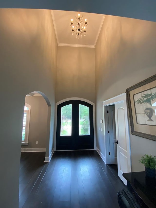 foyer entrance with a towering ceiling, dark hardwood / wood-style flooring, a wealth of natural light, and a notable chandelier