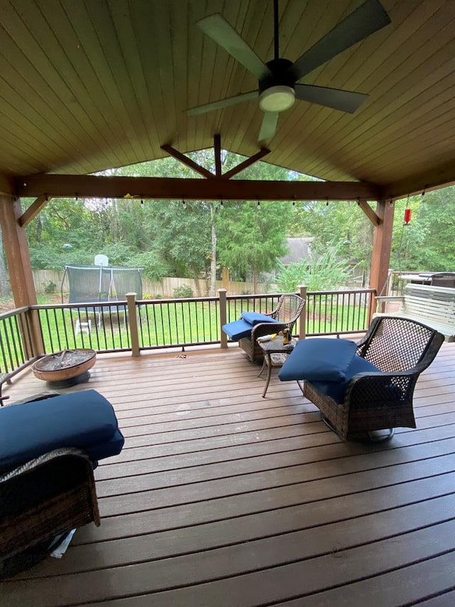 deck featuring a lawn, ceiling fan, a grill, and a trampoline