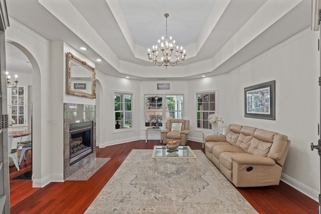 living room with a raised ceiling, a chandelier, a premium fireplace, and dark hardwood / wood-style floors