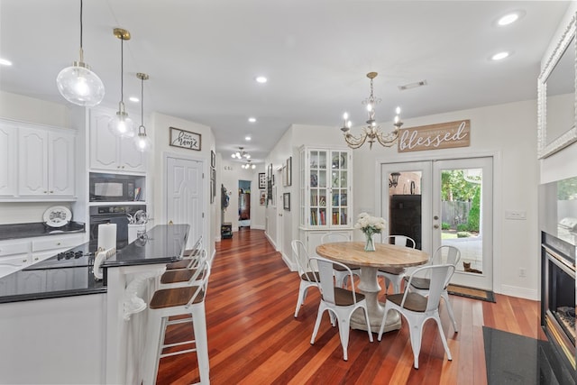 dining space featuring light wood-type flooring, french doors, and a chandelier