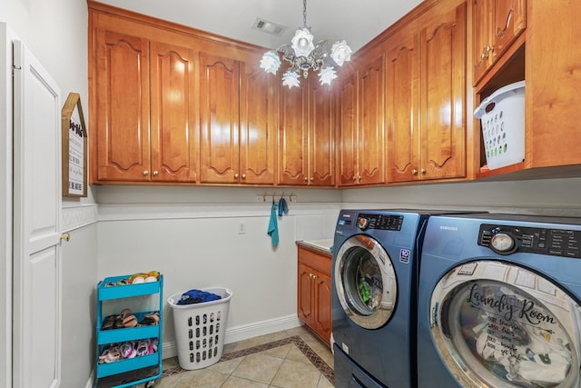 laundry room featuring washing machine and dryer, cabinets, a notable chandelier, and light tile patterned floors