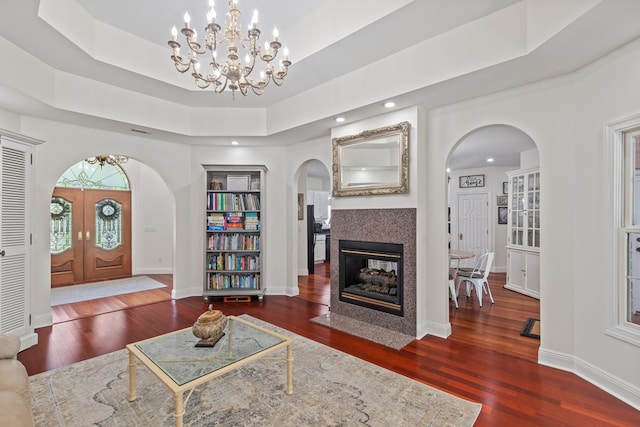 living room featuring a tray ceiling, dark hardwood / wood-style flooring, french doors, and a tiled fireplace