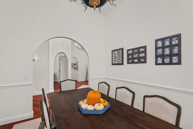 dining room with dark wood-type flooring and a towering ceiling