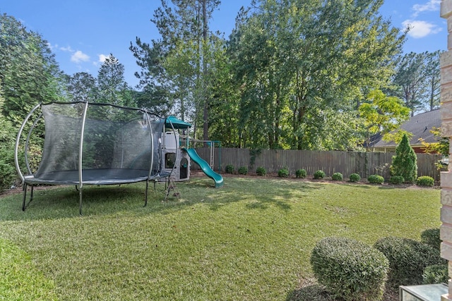 view of yard featuring a trampoline, a fenced backyard, and a playground