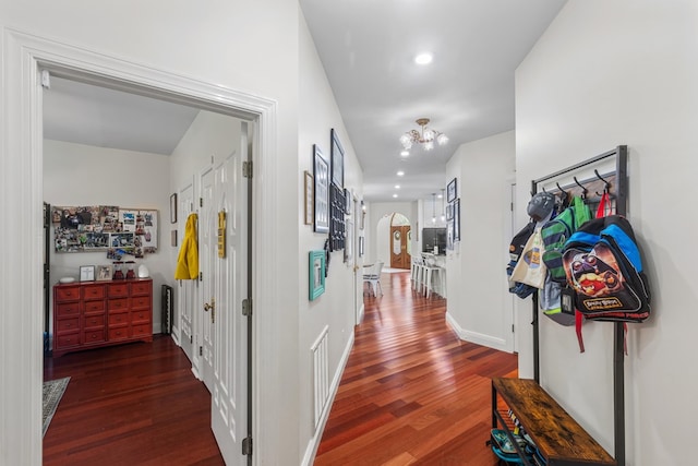 hall featuring dark wood-type flooring and a notable chandelier