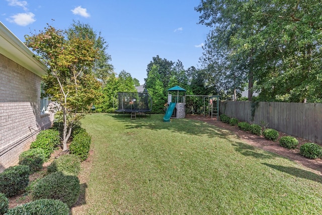 view of yard featuring a trampoline, a fenced backyard, and a playground