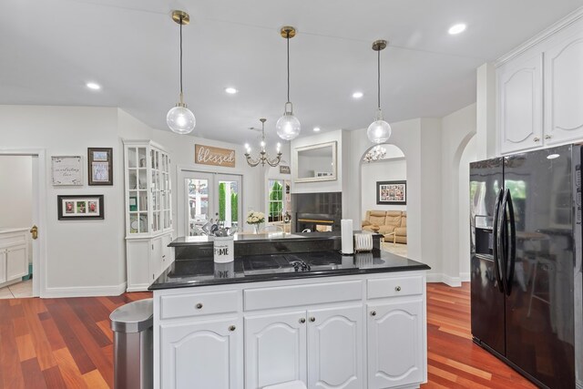 kitchen with white cabinets, dark countertops, wood finished floors, pendant lighting, and black appliances