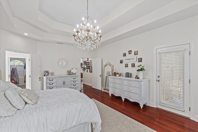 bedroom featuring a tray ceiling, dark hardwood / wood-style floors, and access to exterior