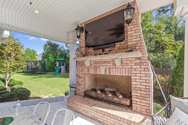 view of patio featuring a trampoline, an outdoor brick fireplace, a playground, and fence