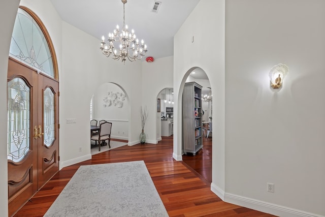 foyer with a chandelier, dark wood-type flooring, and a high ceiling