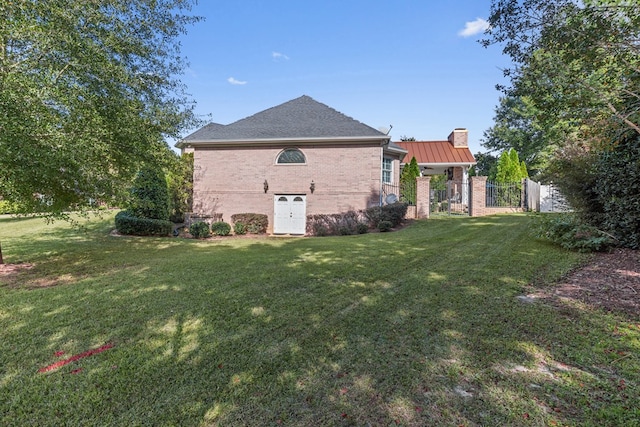 exterior space with brick siding, a chimney, fence, and a yard