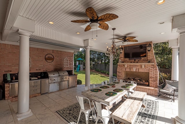 view of patio with a ceiling fan, outdoor dining space, fence, an outdoor kitchen, and an outdoor brick fireplace