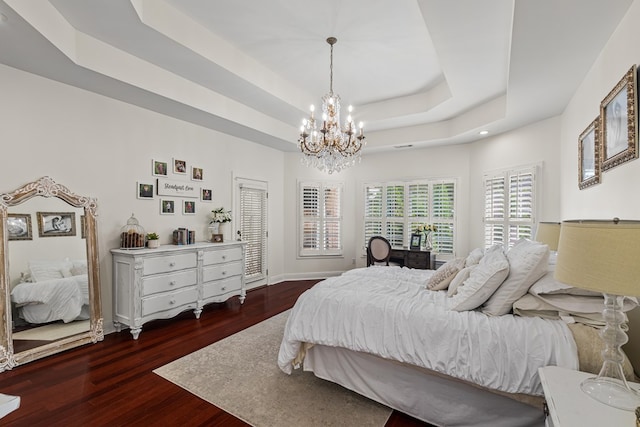 bedroom featuring wood finished floors, a chandelier, a raised ceiling, baseboards, and recessed lighting