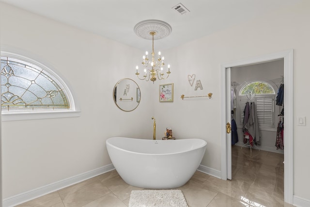 bathroom with a soaking tub, baseboards, visible vents, and marble finish floor