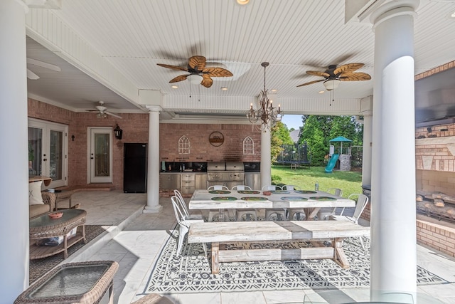 view of patio / terrace featuring ceiling fan, a playground, a grill, and exterior kitchen