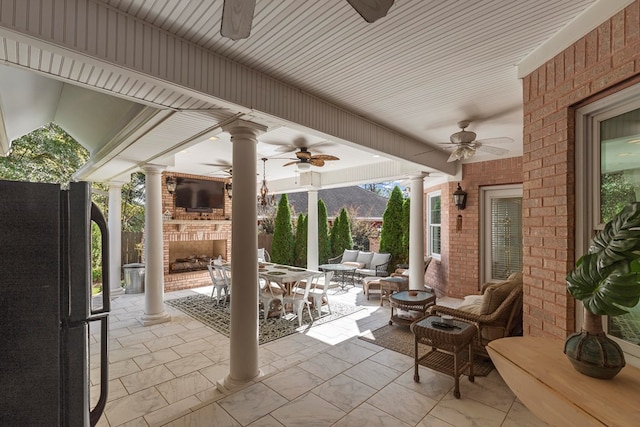 view of patio / terrace featuring ceiling fan and an outdoor living space with a fireplace