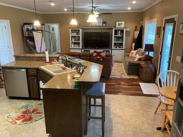 kitchen featuring pendant lighting, sink, stainless steel dishwasher, an island with sink, and light stone counters