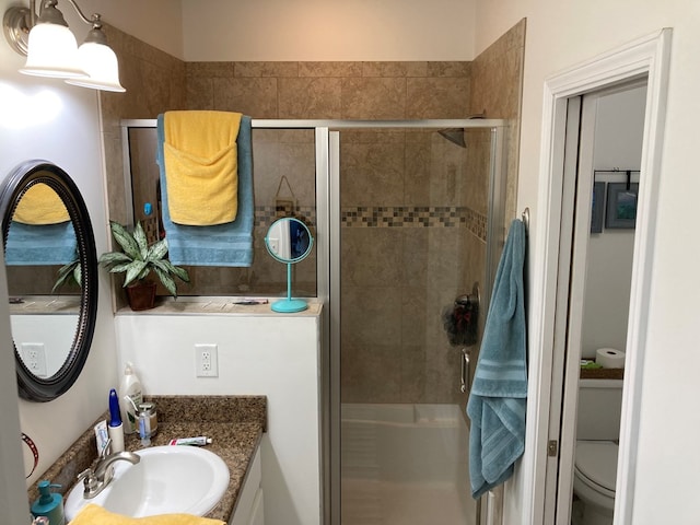 bathroom with toilet, an enclosed shower, and vanity