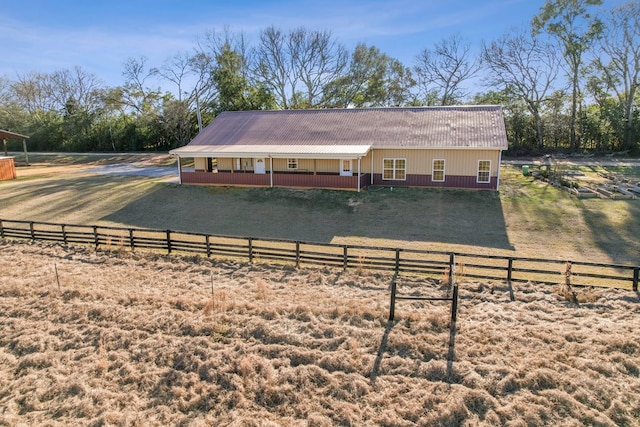 back of house featuring a porch, a yard, and a rural view