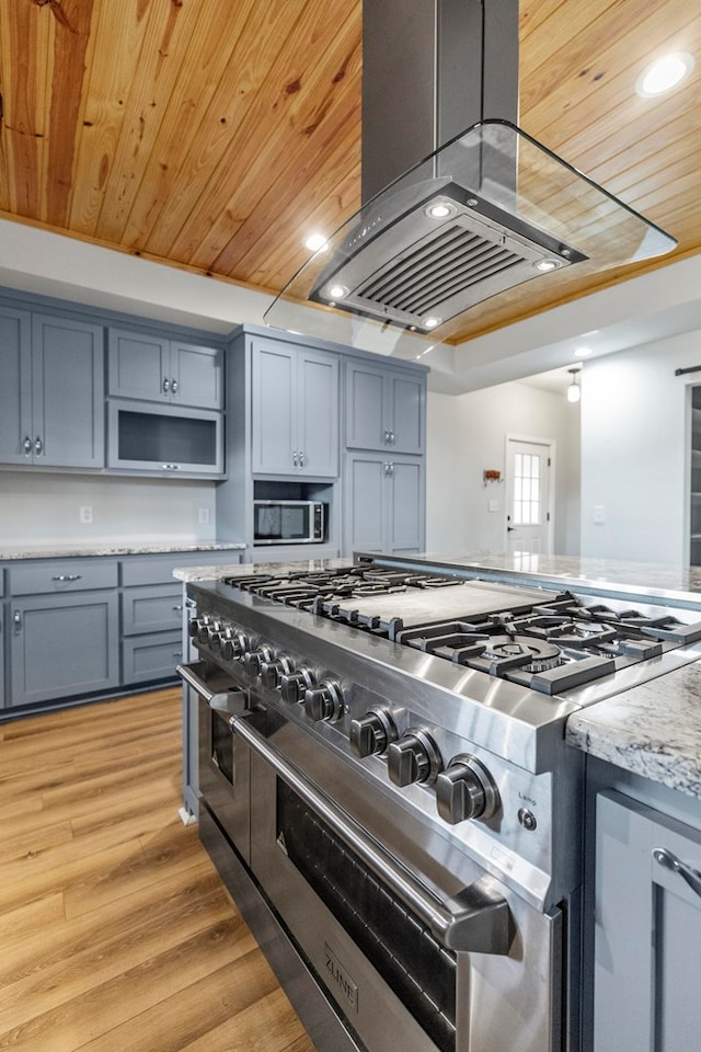 kitchen featuring wooden ceiling, light stone counters, light wood-type flooring, island exhaust hood, and appliances with stainless steel finishes