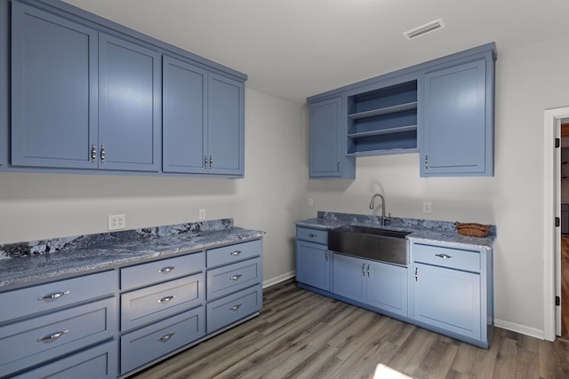 kitchen featuring sink, blue cabinetry, and wood-type flooring