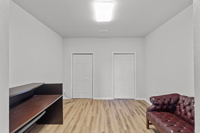 living area with a textured ceiling and light wood-type flooring