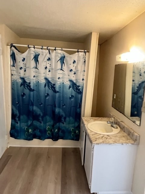 full bath featuring vanity, shower / bath combination with curtain, and wood finished floors