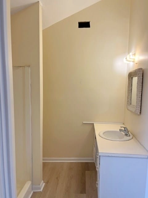 full bathroom featuring vanity, wood finished floors, and baseboards