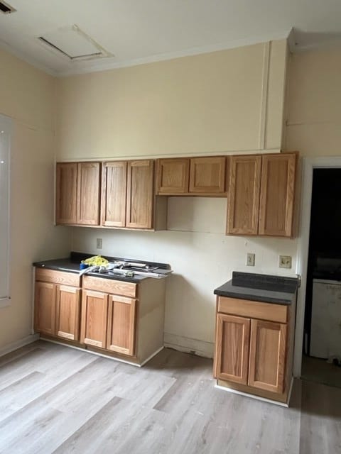 kitchen featuring light wood-style floors, dark countertops, and brown cabinetry