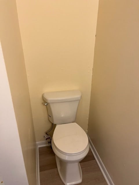 bathroom with baseboards, toilet, and wood finished floors